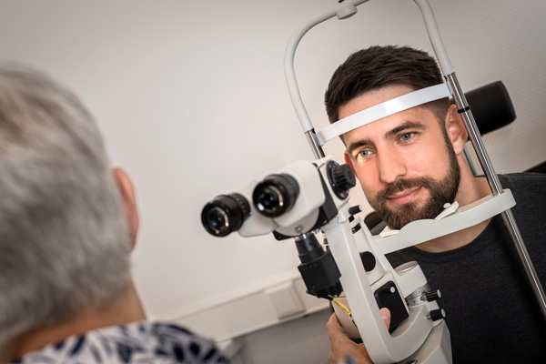 Eye doctor examining a patient with a slit lamp during an eye exam, close to the lens image side.